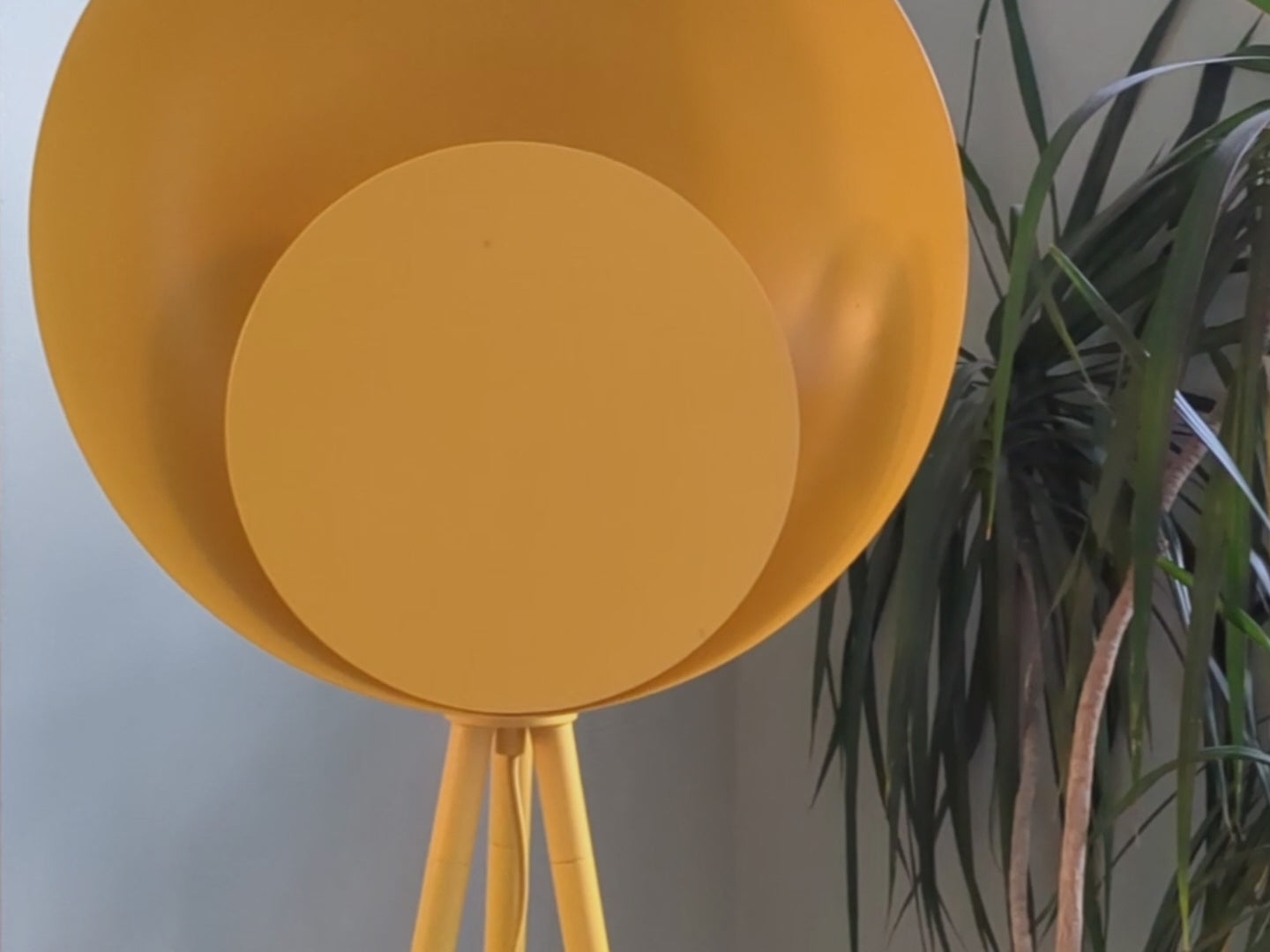 A bright yellow tripod base suspends an oversized bright yellow dome head with a diffused, integrated LED light. Light off and then on.
