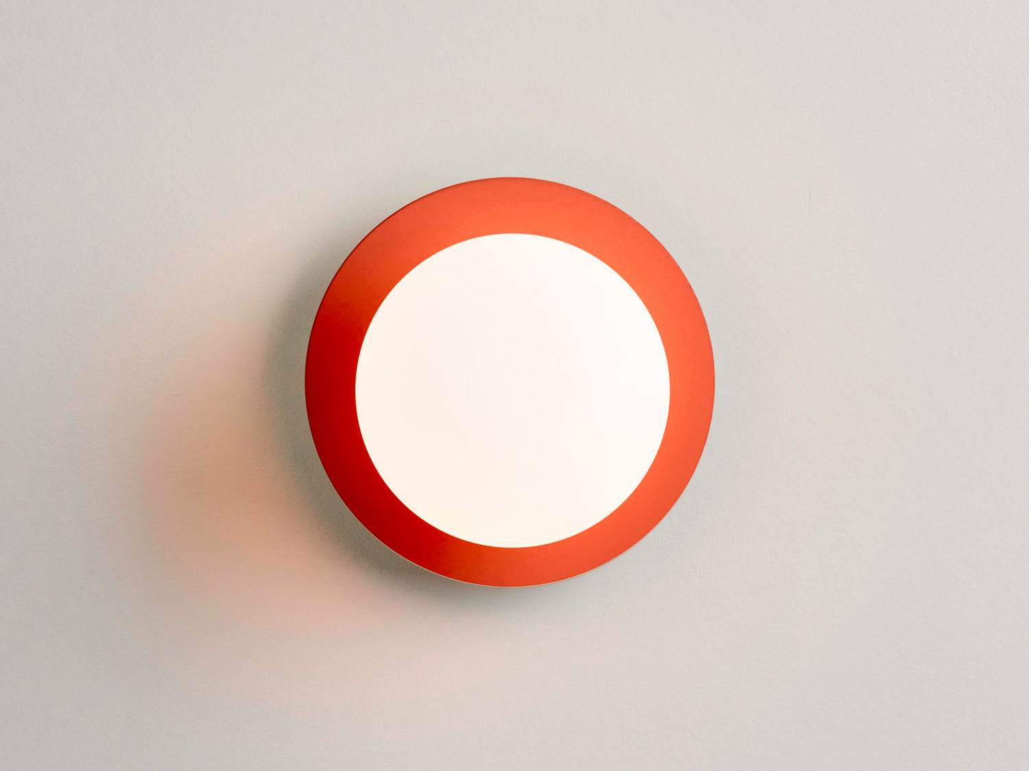 An opal glass shade sits upon an orange metal disk. Light is on. Suitable for bathrooms.