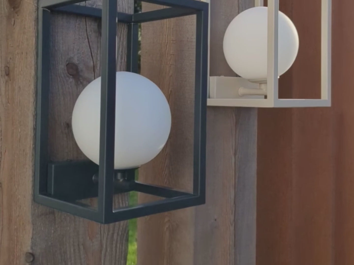 A traditional charcoal-grey coloured lantern style outdoor light, with deconstructed walls and a glass globe that sits within.