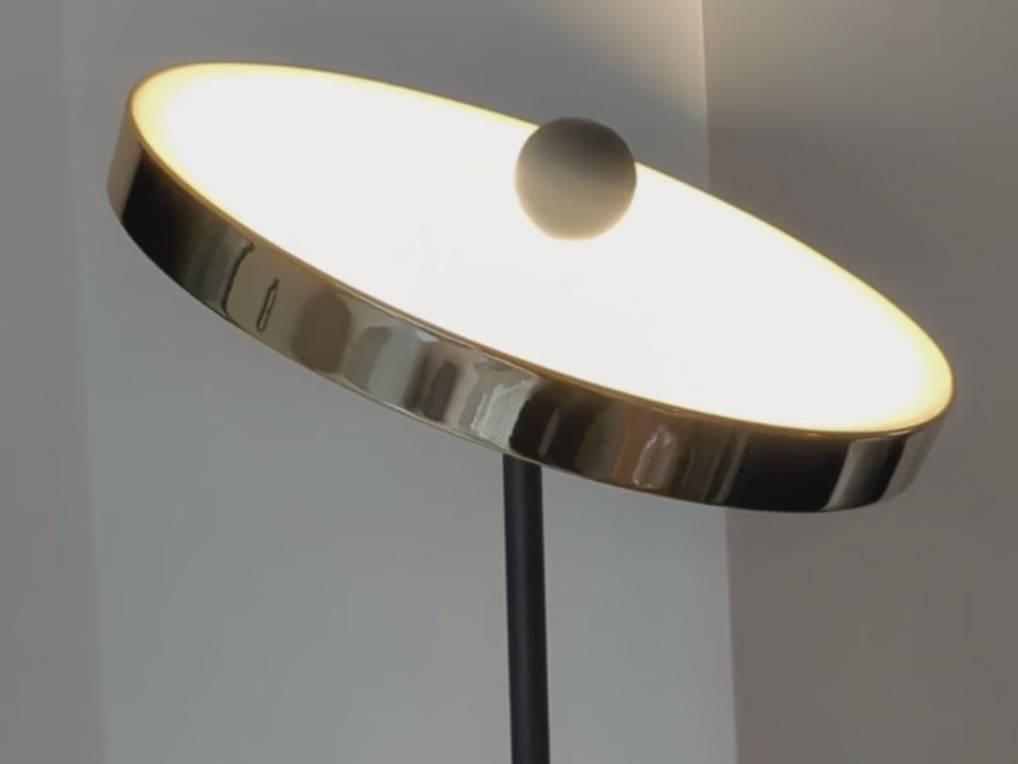 Brass floor lamp with a solid brass base and integrated LED round head that can be angled in multiple directions. Light is on and shown in different locations in a living room.