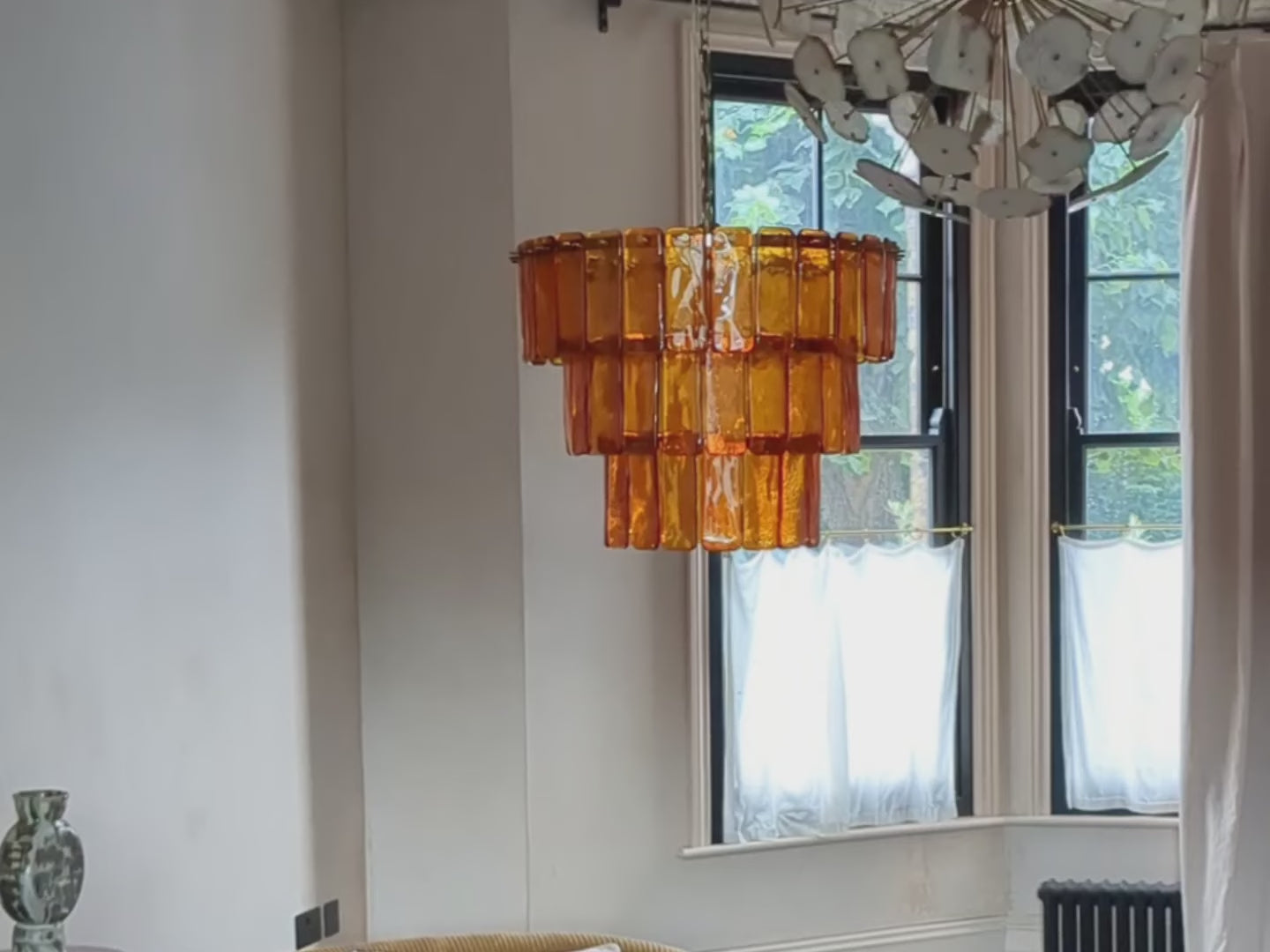 66 amber-coloured glass pieces that are oblong-shaped are mounted on 3 tiered, brass arms.