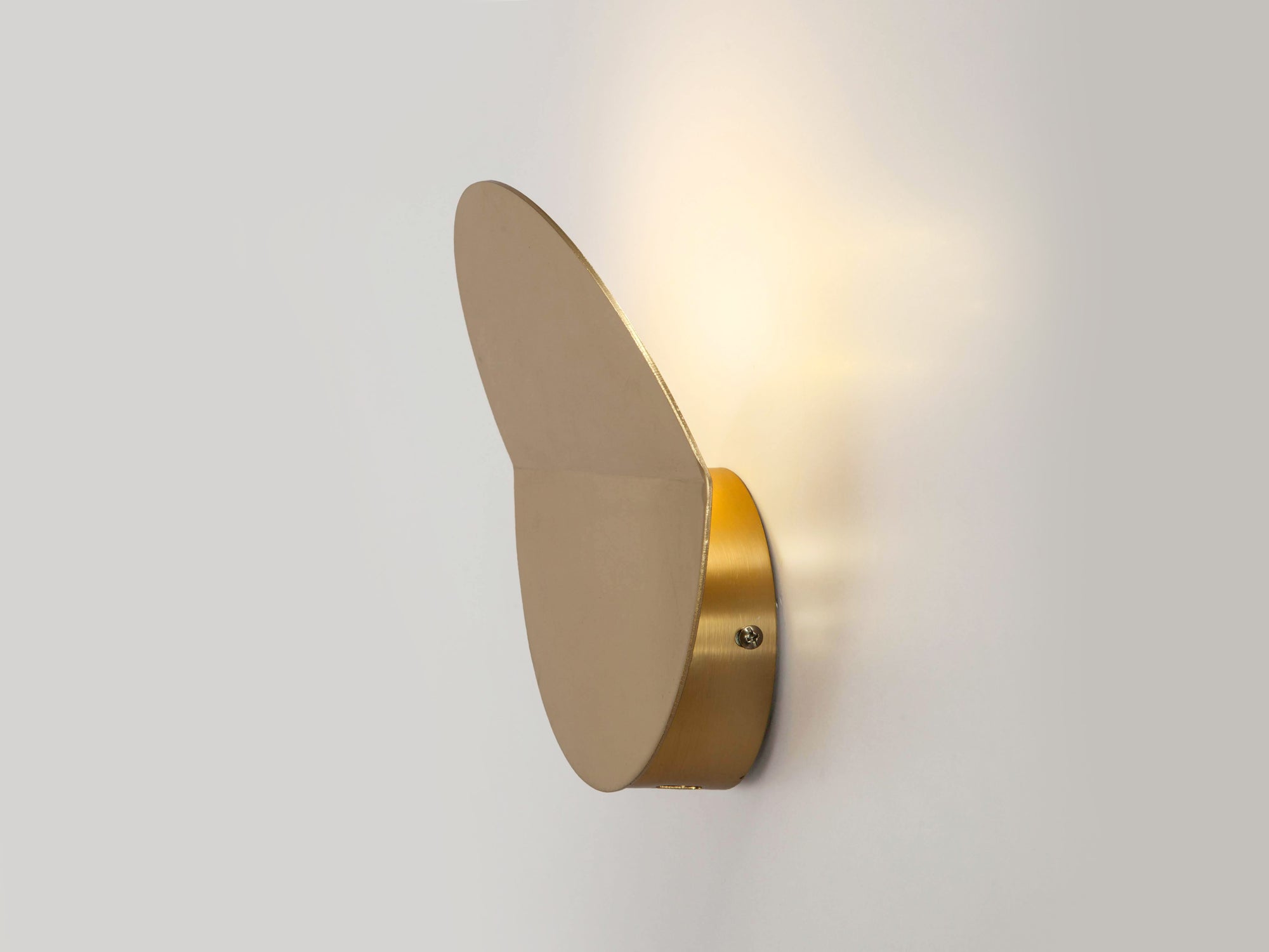 Side profile of a brass circular wall light that sits flush to the wall, with a subtle fold and integrated LED bulbs.