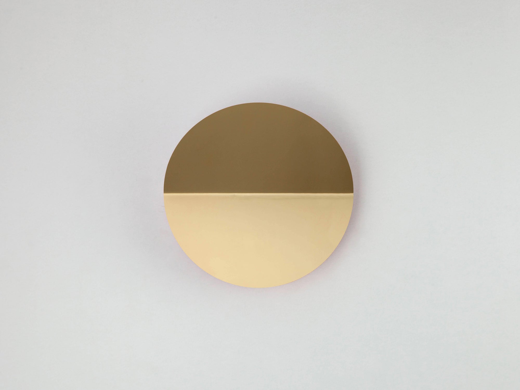 A brass circular wall light that sits flush to the wall, with a subtle fold and integrated LED bulbs.