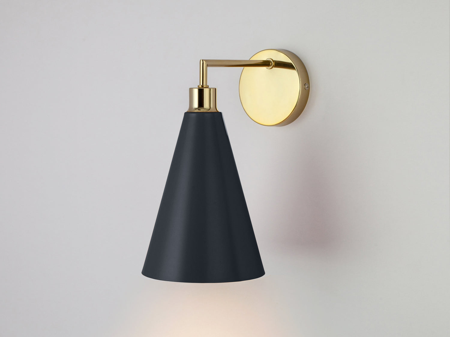 A brass wall fixture suspends a charcoal cone-shaped metal shade.